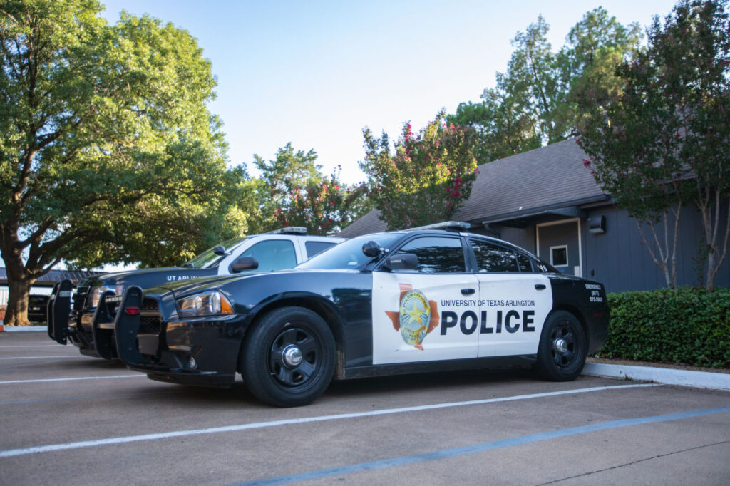 Two UT Arlington police patrol vehicles parked in a designated campus parking lot.