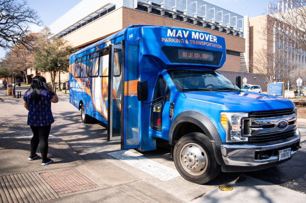 A blue UTA Mav Mover shuttle bus parked at a campus transit stop.