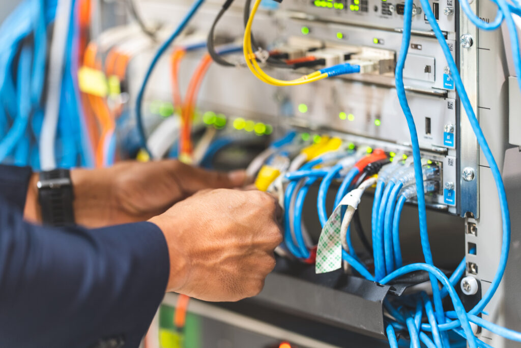 Close-up of hands organizing blue Ethernet cables in a high-density network server rack.