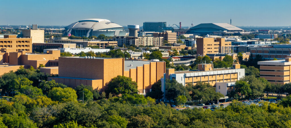 Panoramic skyline view of UT Arlington campus buildings with AT&T Stadium in the distance.